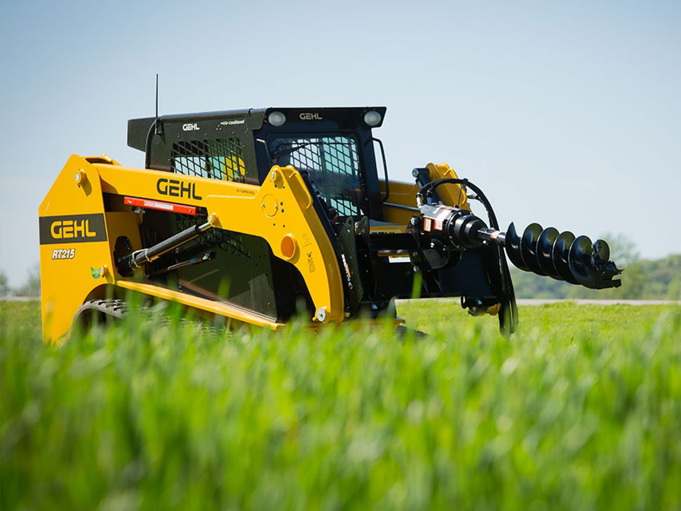 Image showing Danuser EP 1020 Auger Drive on Gehl RT215 Skid Steer moving through grassy terrain