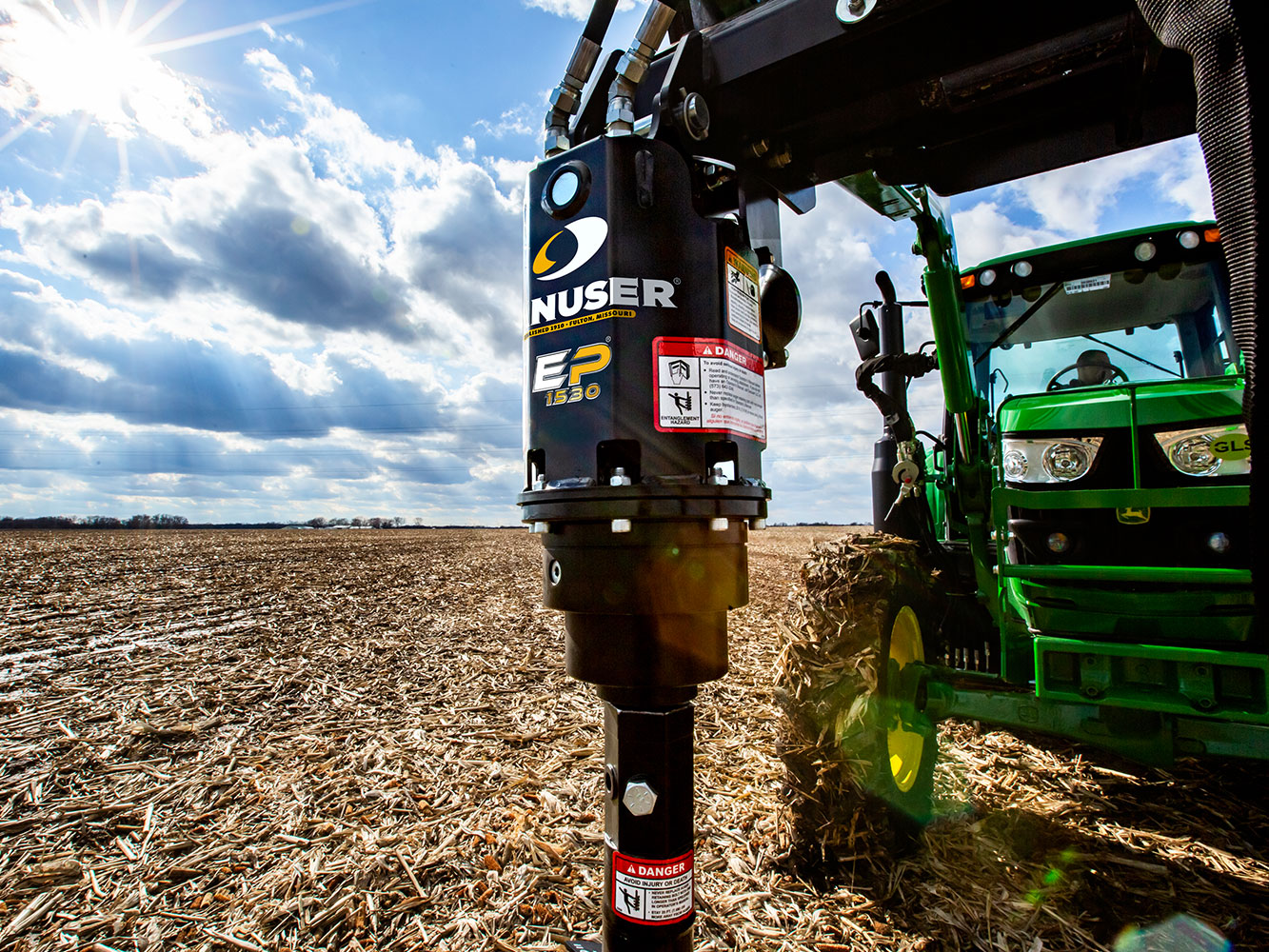 Image showing close-up of Danuser EP 1530 Auger Drive on John Deere tractor in open farm field, drilling into ground