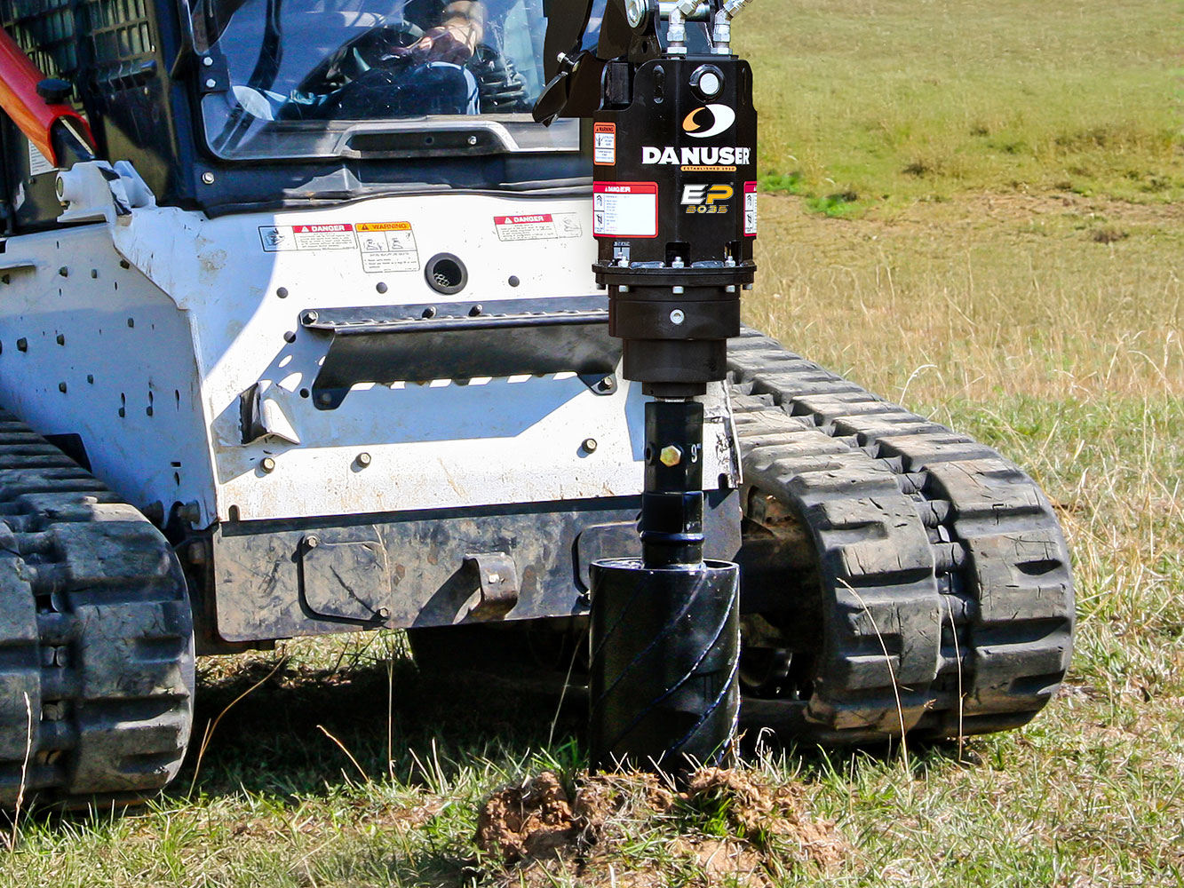 Image showing Danuser EP 2035 Auger Drive on Bobcat Skid Steer with Wobble Auger drilling in grassy field