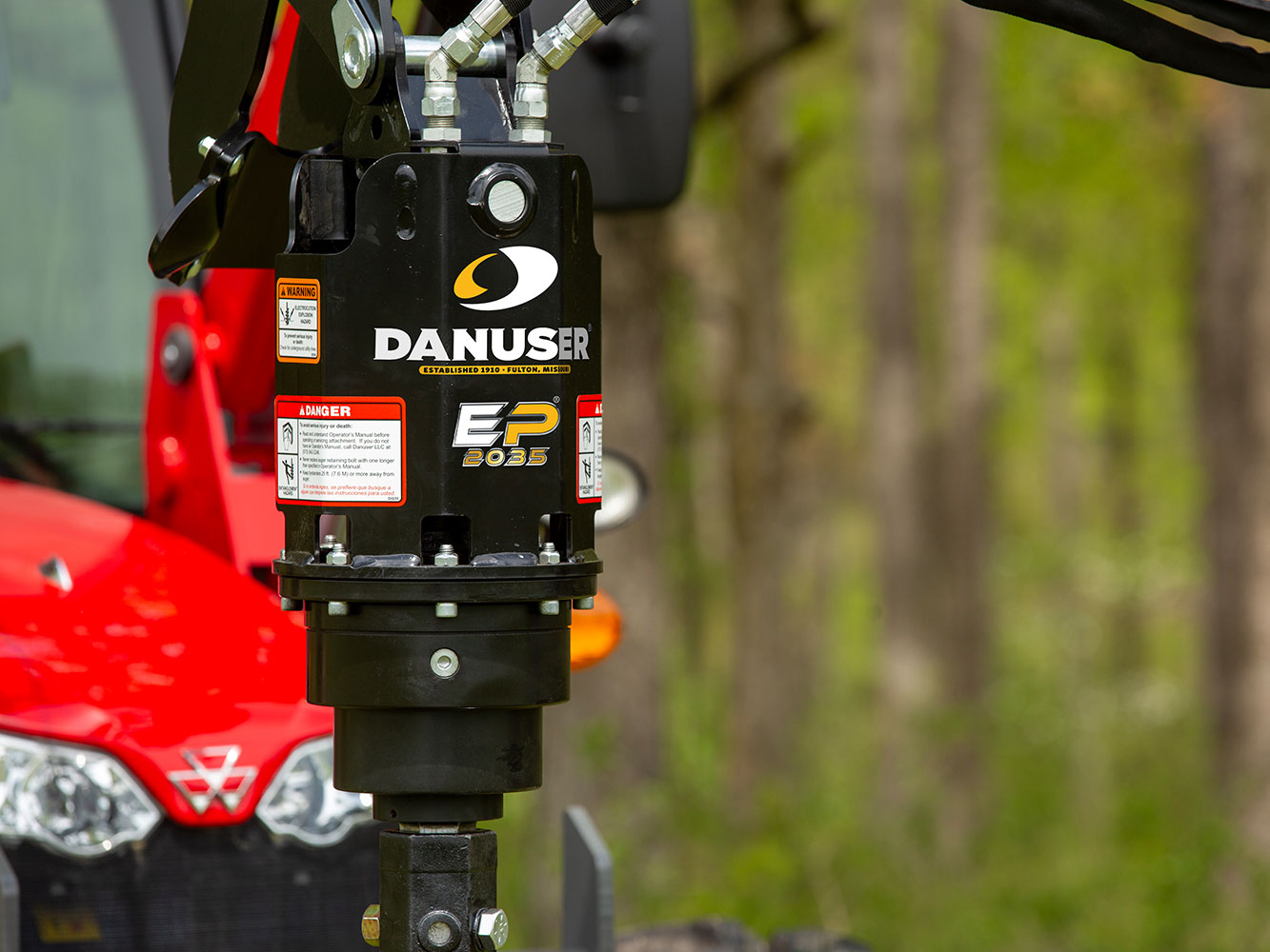 Image showing close-up of Danuser EP 2035 Auger Drive mounted on red Massey Ferguson tractor, showing logos and safety labels