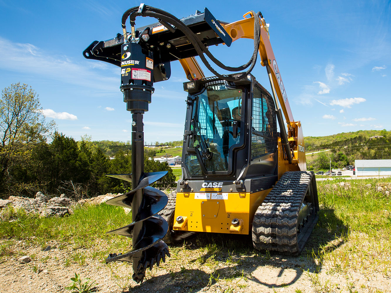 Image showing Danuser EP 615 Auger Drive on Case TR340 Skid Steer in grassy area and building visible in background