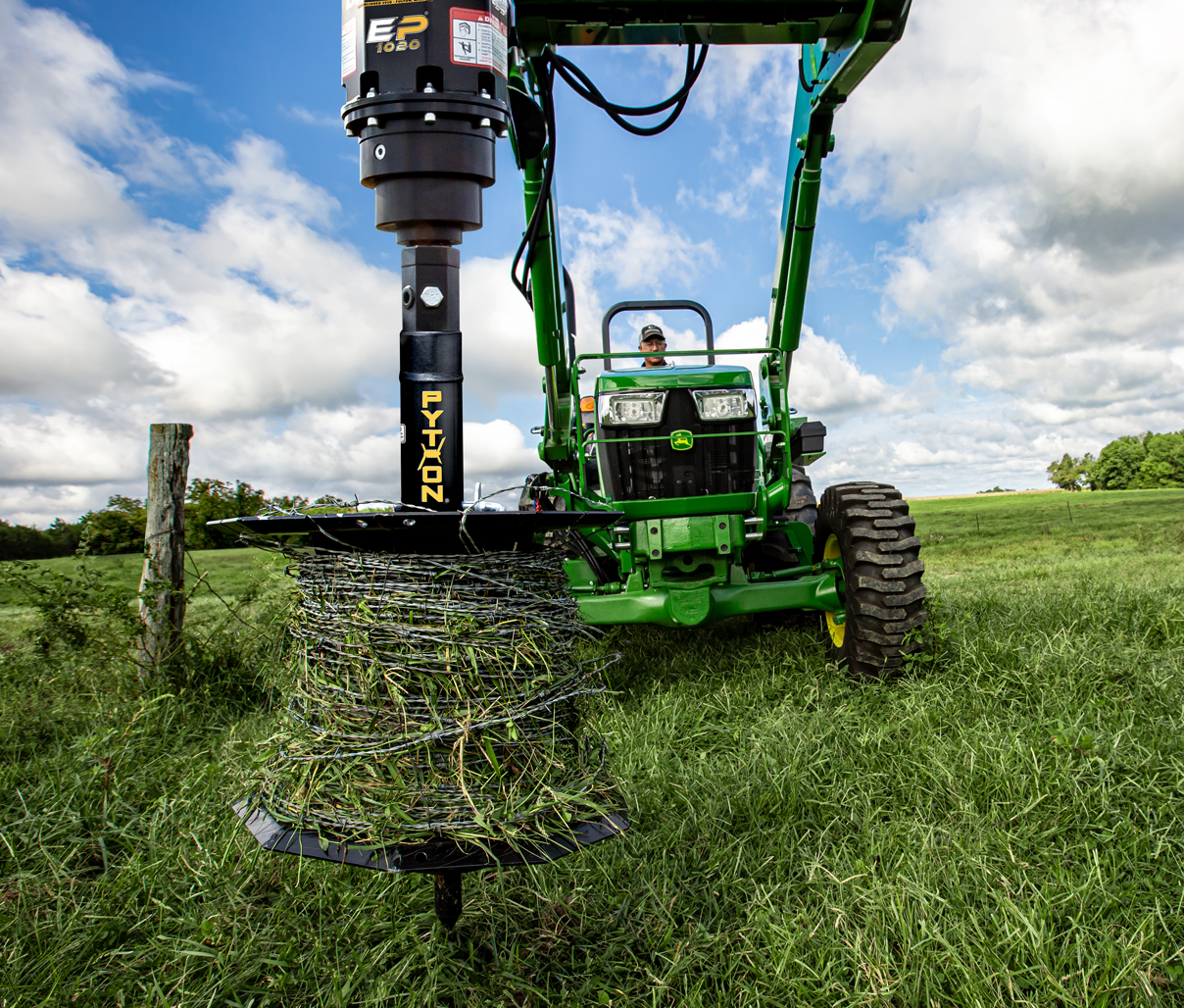 Image showing Danuser Python Wire Winder on John Deere 5055E with barbed wire in grassy open field near wooden fence post