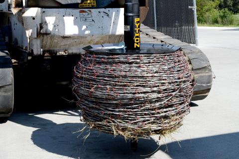 Image showing Danuser Python Wire Winder mounted on Bobcat T870, with barbed wire and grass tangled around the attachment