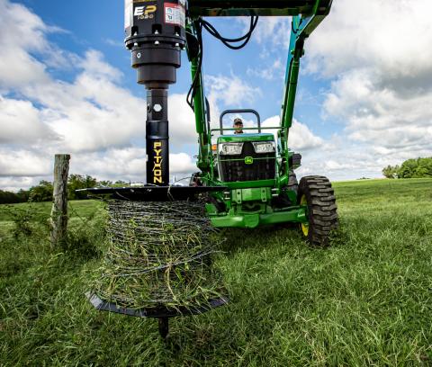 Image showing barbed wire on Danuser Python Wire Winder mounted to John Deere 5055E in grassy field near wooden post
