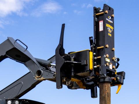 Image showing Front-right close-up of Danuser Hornet T8-RR on John Deere 333G Skid Steer holding wood post with clear blue sky in background