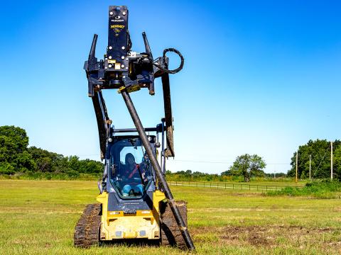 Image shows Danuser Hornet T7 using grapple on John Deere 333G Skid Steer to move metal post for post installation in open field