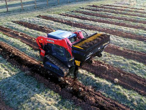 Image showing Danuser Mega Mixer on Kubota SVL 75-2 Skid Steer dispensing compost in tilled farm field