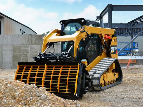 Image showing Danuser Mega Mixer on CAT 289D Skid Steer scooping gravel at construction site with concrete wall and steel frames in background