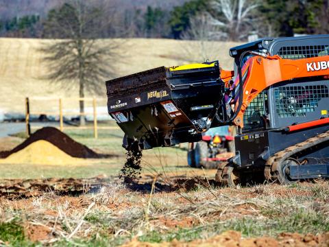 Image showing Danuser Mega Mixer on Kubota Skid Steer spreading soil in field during agricultural work, shown in action