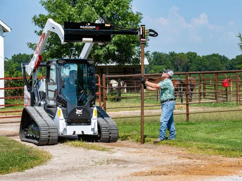 Image shows Danuser T3 on Bobcat T75 drives post into ground while man holds it in place